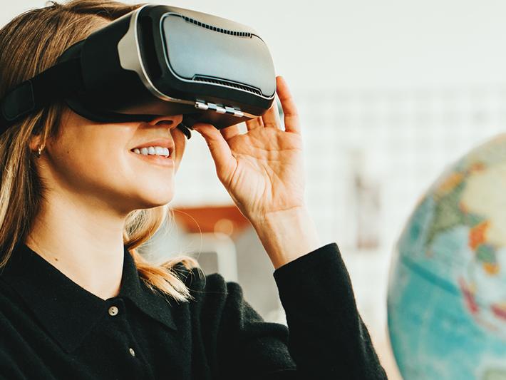 Young woman wearing virtual reality headset with globe in background