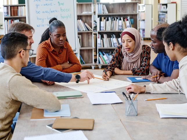 Teachers and students working on a project together in the library