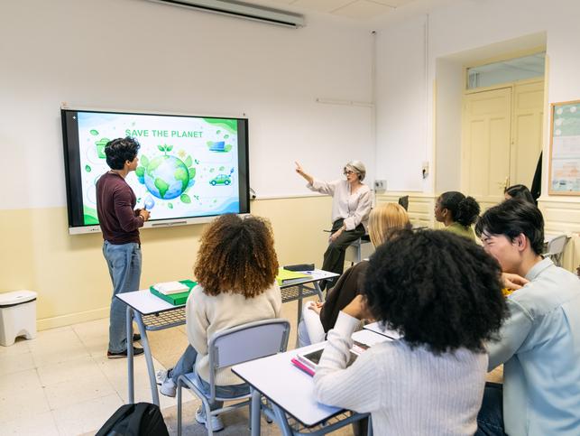 University students having a discussion about climate change while one presents a poster titled "Save the planet"