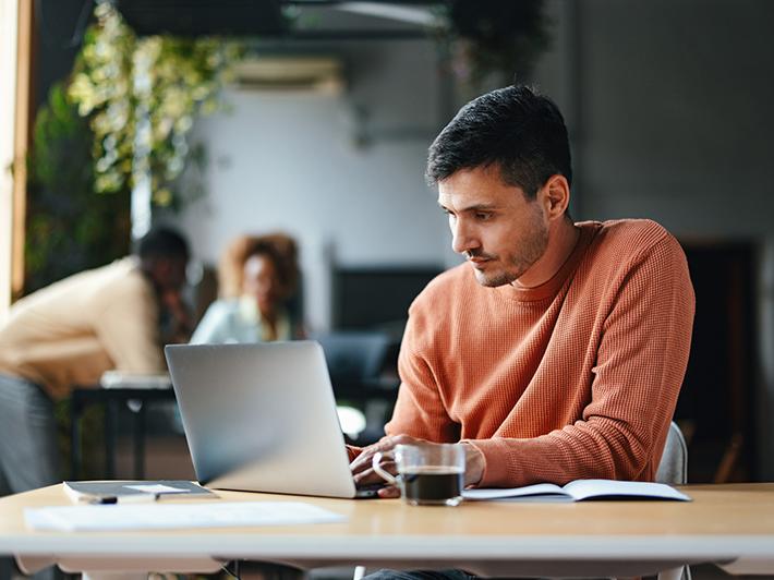 Caucasian male working at laptop in cafe