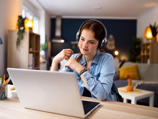A student with headphones on her laptop
