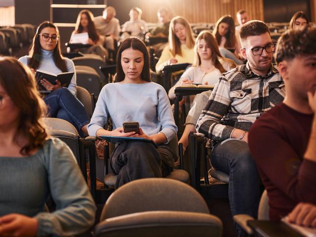 Students look at their phones in the lecture hall