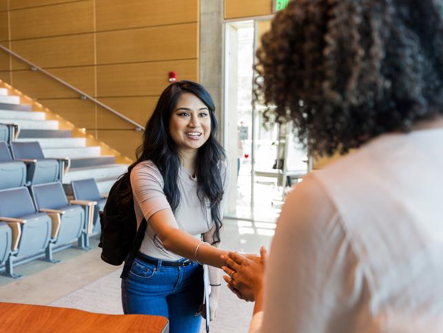 A staff member welcomes a student