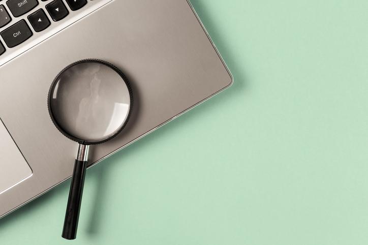 A magnifying glass sits on a laptop