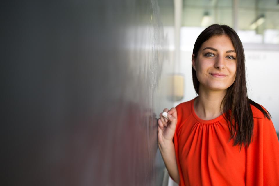 A teacher standing next to a blackboard