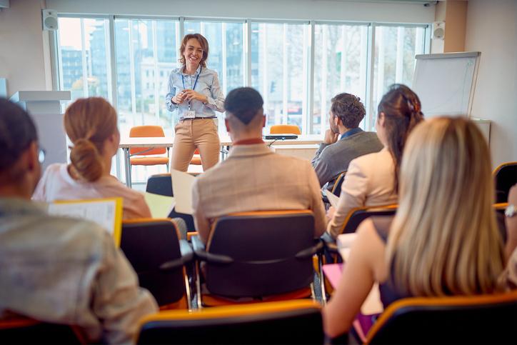 A group of people listen to a lanyard-wearing speaker