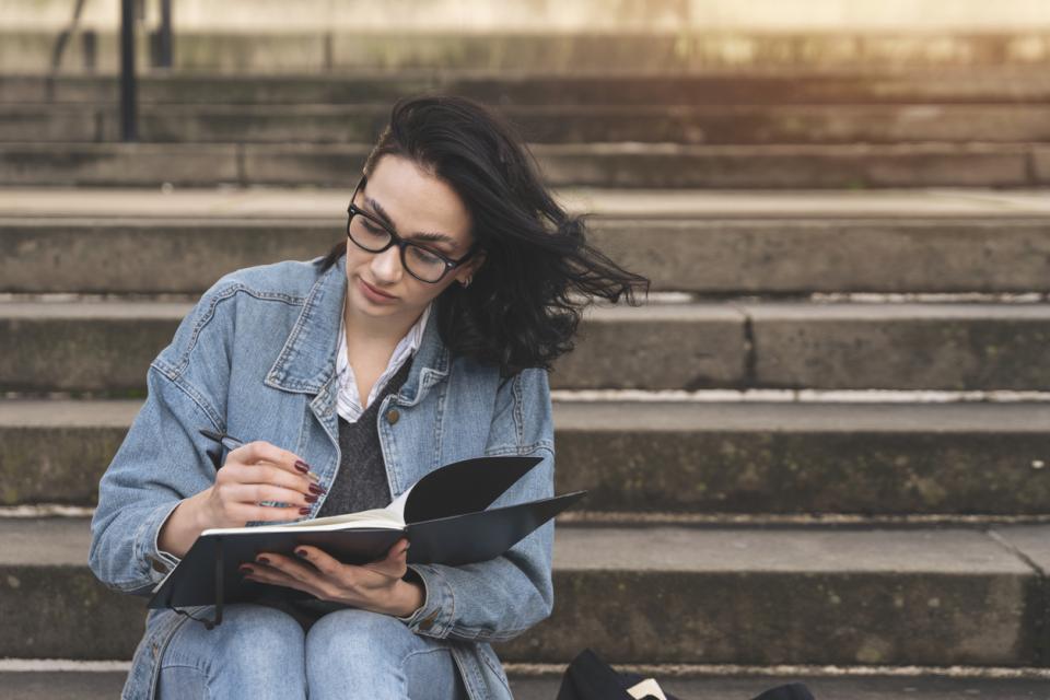 A woman writing in a journal on some steps