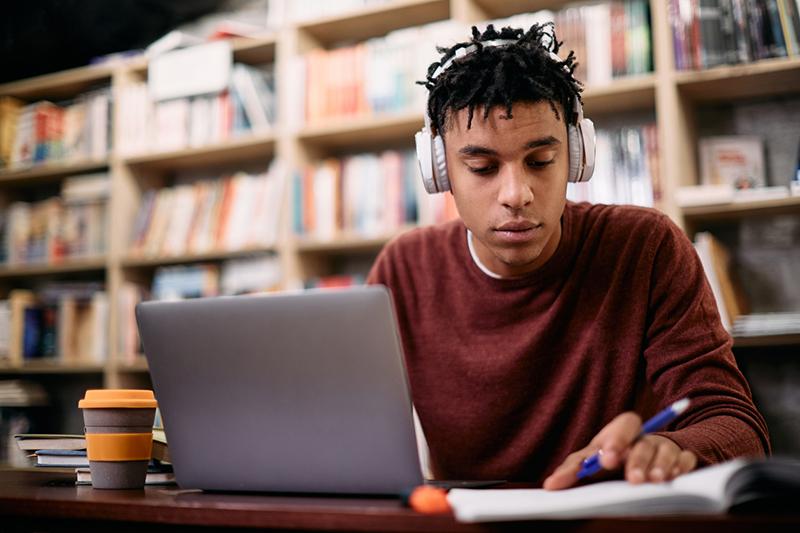 Young black student in headphones at laptop