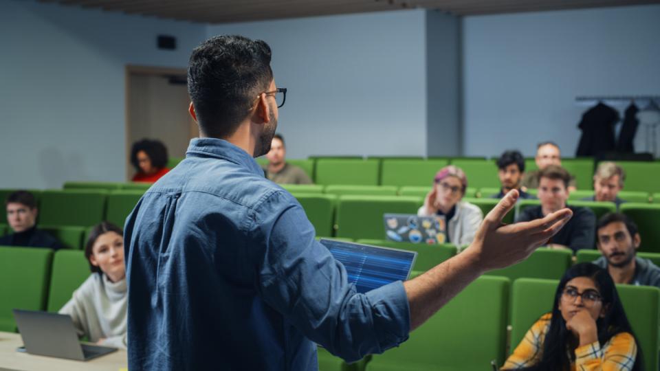 A lecturer at the front of class presenting to students 