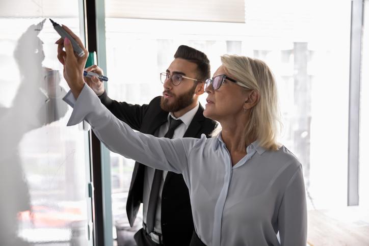 Two people write on a whiteboard