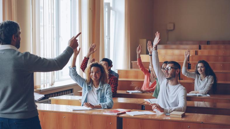 Students raise their hands in a lecture hall