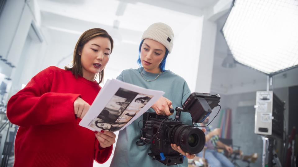 Students working on a film treatment with a camera in hand