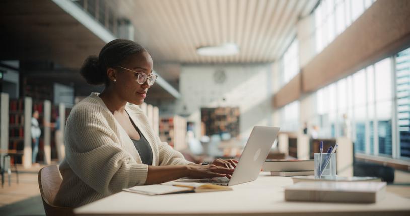 A young woman works at her laptop at the library