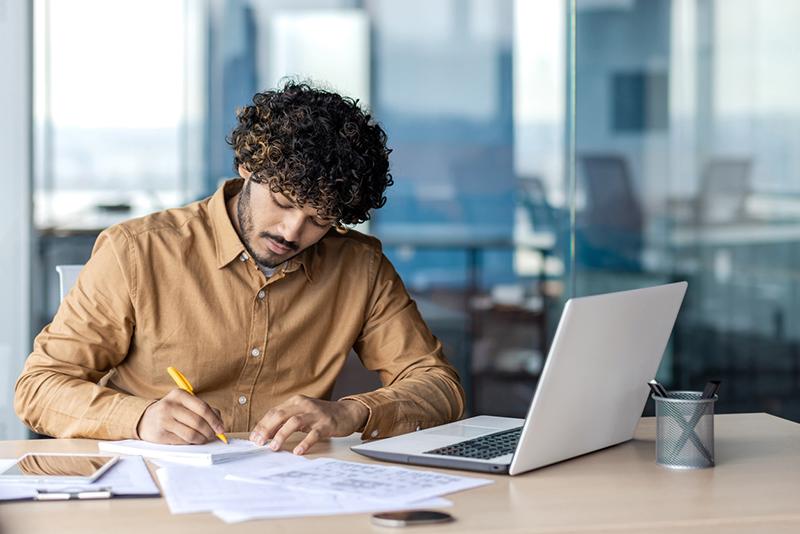 Young man working on document with laptop