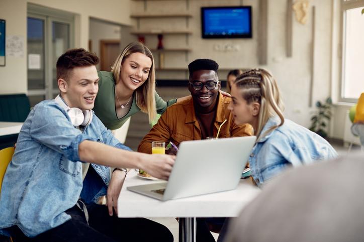 Students laugh around a laptop