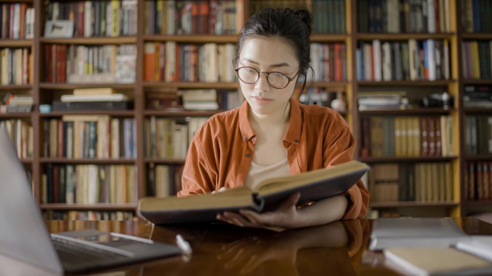 A woman researching at a desk in a library