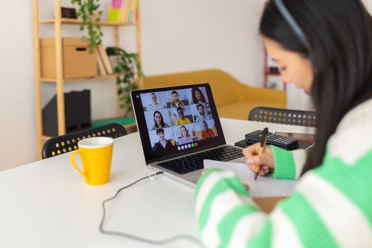 A student takes notes during a group Zoom call