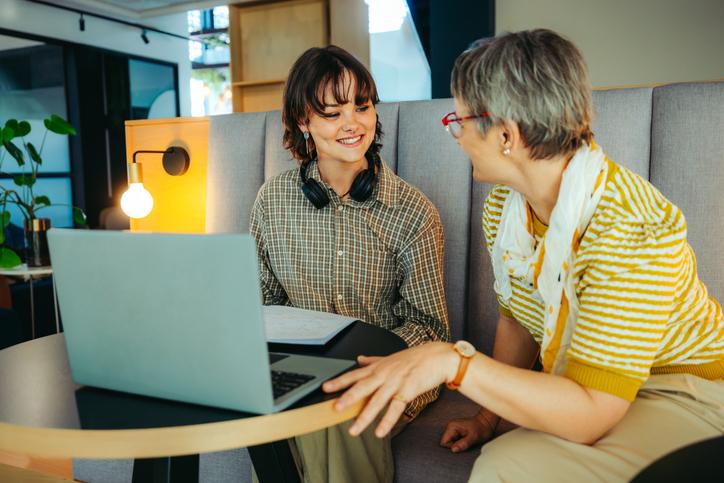 A mentor helps a student over a laptop