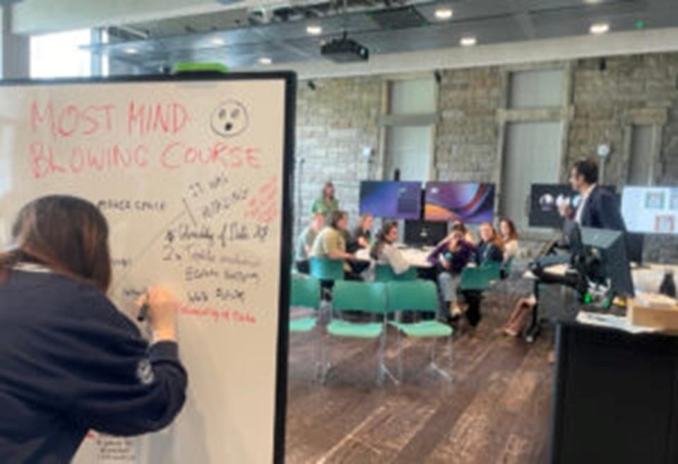 A student responding to a prompt on a whiteboard during 2024's Feedback Fest