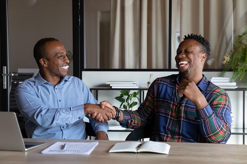 Two black men shaking hands and smiling