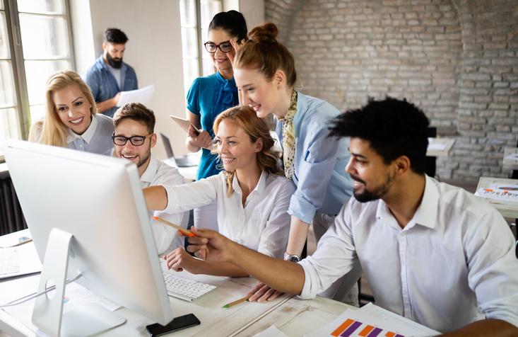 Students work together around a desktop computer