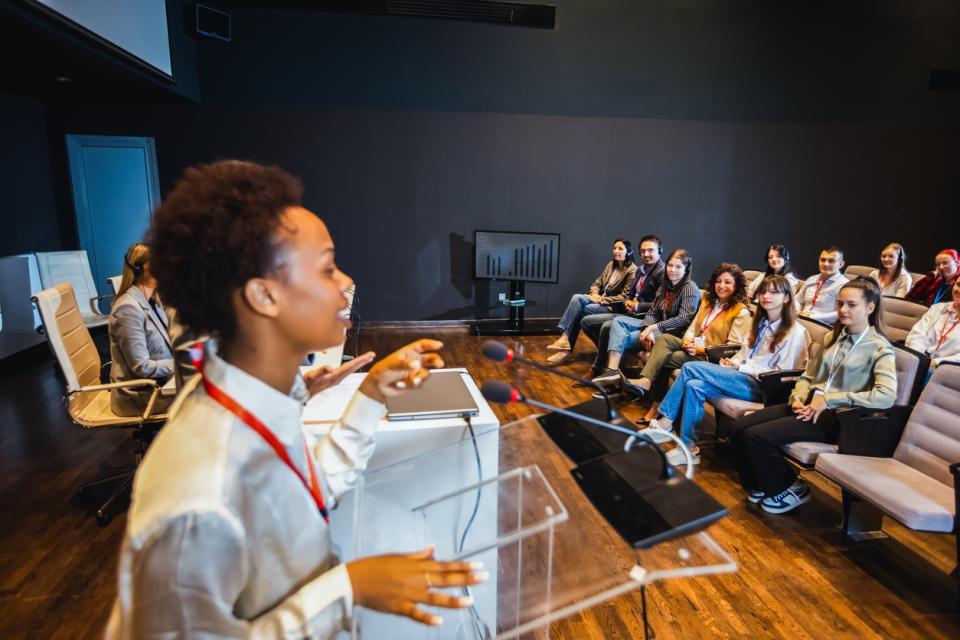 A lecturer at the front of class presenting to students 