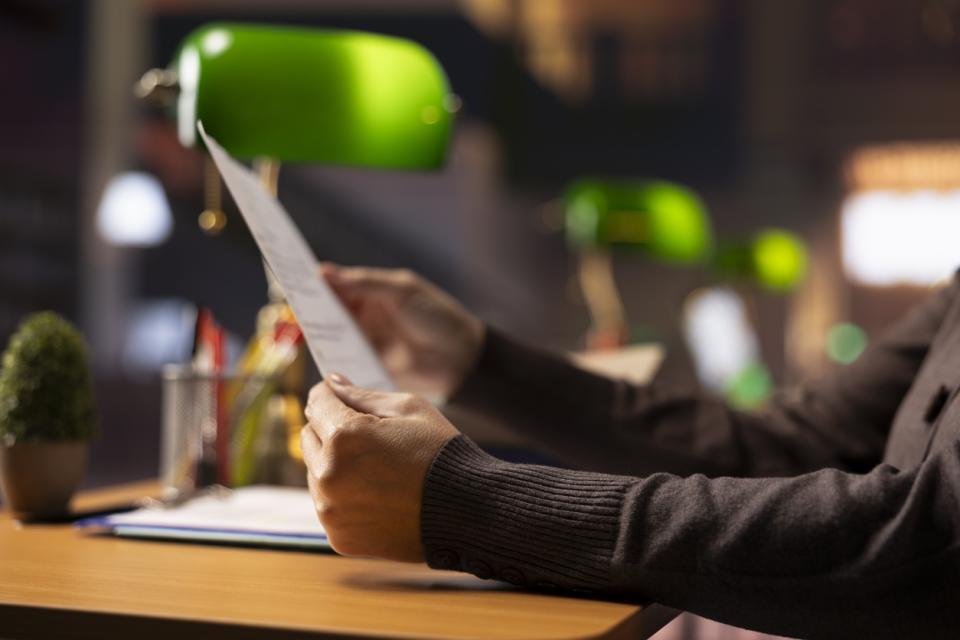 A professor holding a document in a library