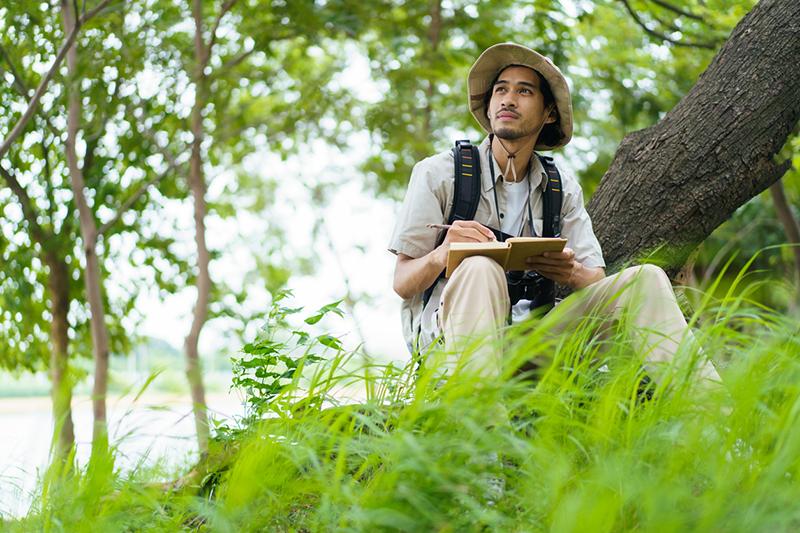 Young Asian man recording observations in nature