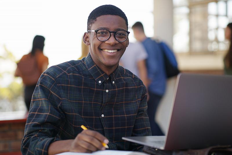Young black male students working outside on laptop