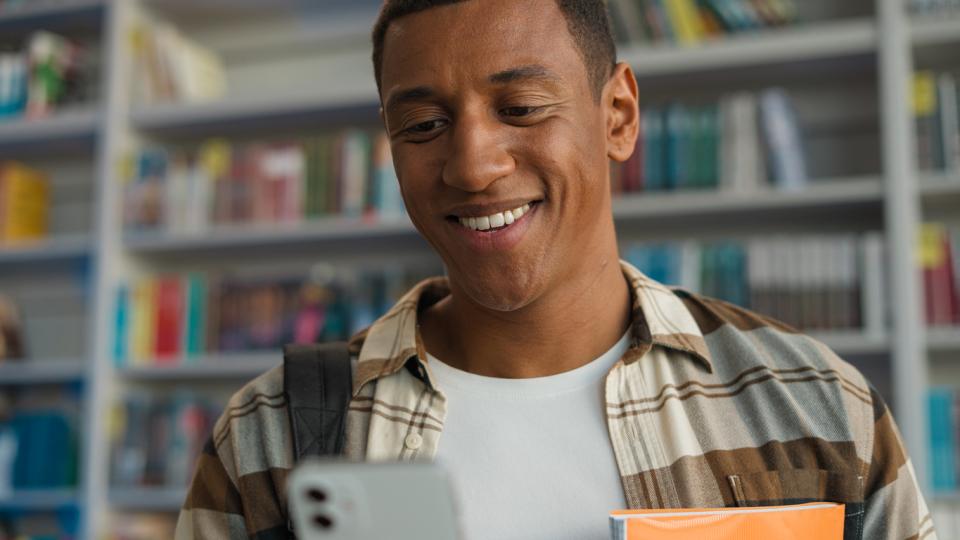 A student looking at his phone in a university library