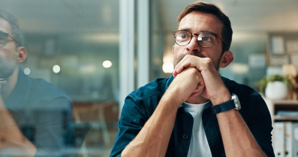 A man sitting at his desk staring into space 