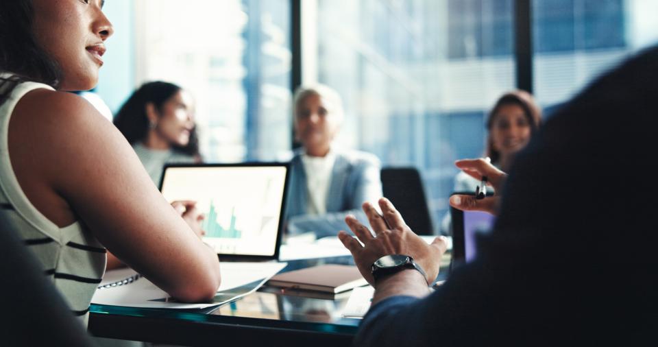 Students in a boardroom working on a company project
