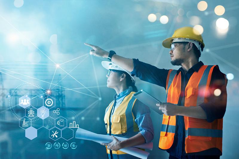 A male and female engineer in safety gear pointing at project