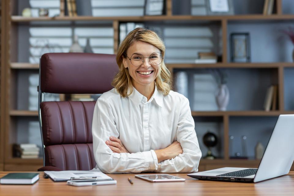 A research supervisor sitting at her desk smiling to camera