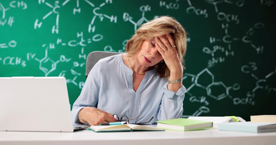 A female academic at her desk with her head in her hand