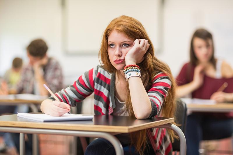 Red-headed female student looking unhappy in an exam