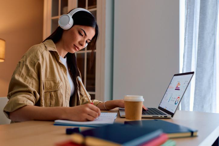 A student works at a laptop with headphones on
