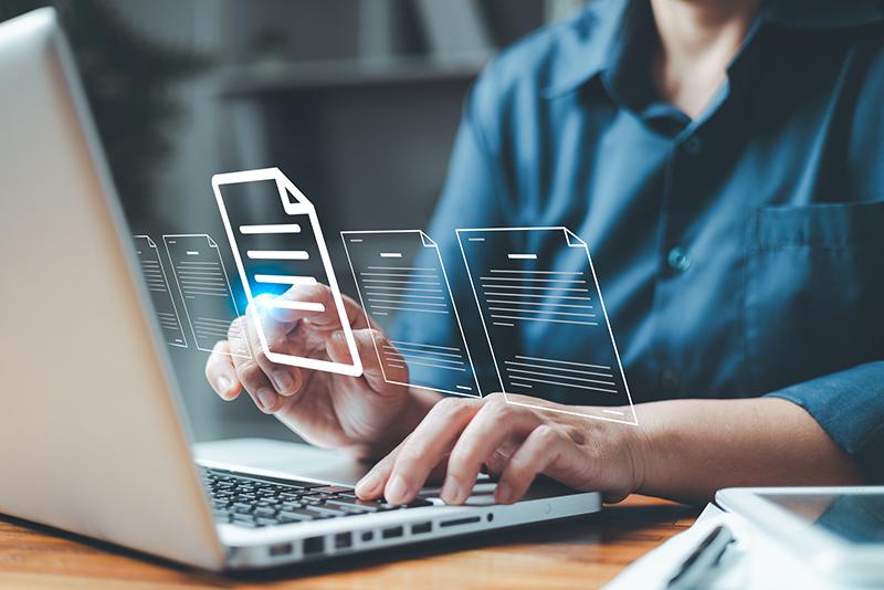 Male student working at laptop surrounded by images of documents
