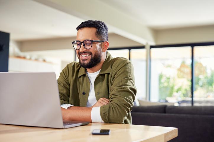 An online learner smiling at classmates on his laptop screen