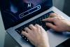 Hands type on a laptop with "AI" on the screen