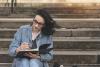 A woman writing in a journal on some steps