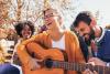 A student with a guitar surrounded by others smiling