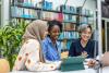 Three young multiracial female scholars in library
