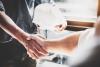 Two people, one carrying a hard hat, shake hands