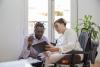 Woman in wheelchair and young black man looking at tablet
