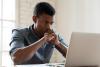 Black male student looking thoughtfully at laptop screen