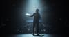 A lecturer is illuminated by the stage lights