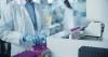 A white-coated figure handles test tubes