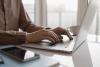 A man types on a laptop, smartphone in the foreground