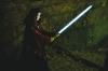 A woman wearing a cape with a light saber in hand, ready for battle